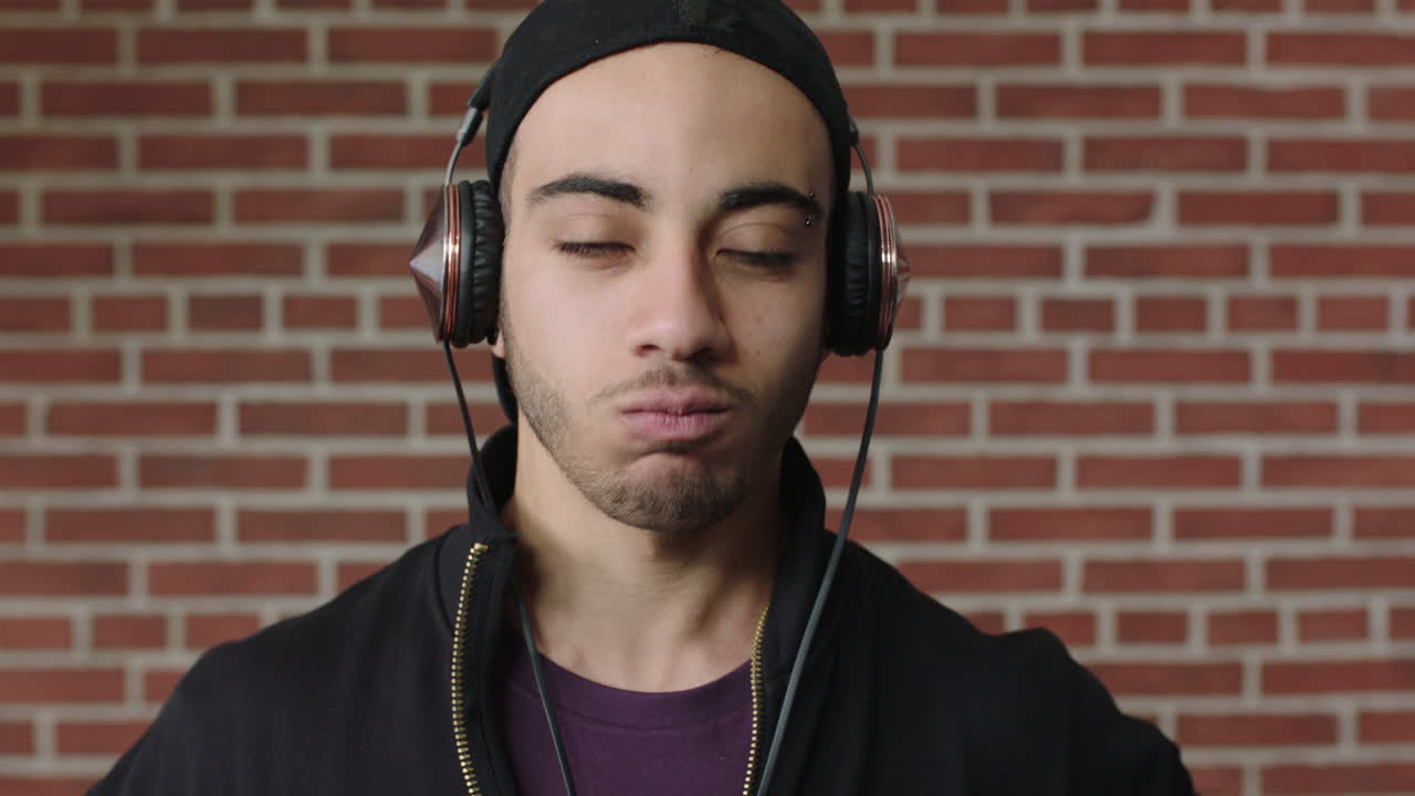 retrato de un joven confiado hombre hispano escuchando música buscando un estudiante serio que quita los auriculares