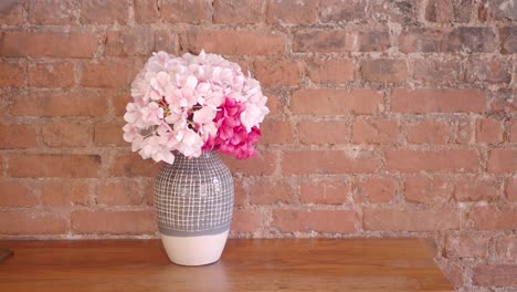 pink and red hydrangea bouquet in gray vase on wooden table