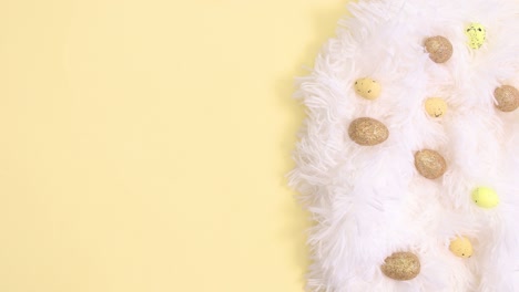 easter white and gold decoration and paper card note appear on bright yellow background. stop motion flat lay