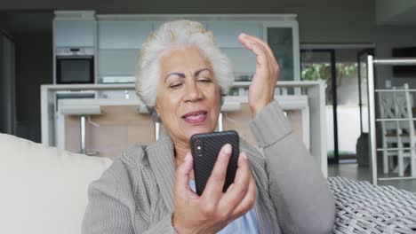 mujer mayor afroamericana soplando besos haciendo una videollamada en el teléfono inteligente en casa