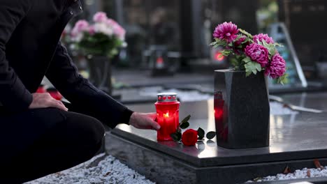 man placing a candle on the grave