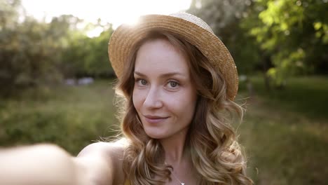 young blonde woman, making selfie in straw hat, funny face, posing at countryside at summer day