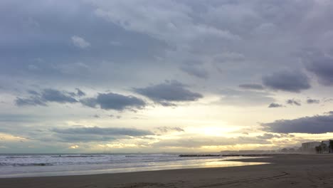 Time-lapse,-storm-clouds-loom-over-Mediterranean-beach-at-sunset