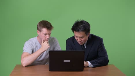 un hombre de negocios japonés maduro y un joven escandinavo trabajan juntos.