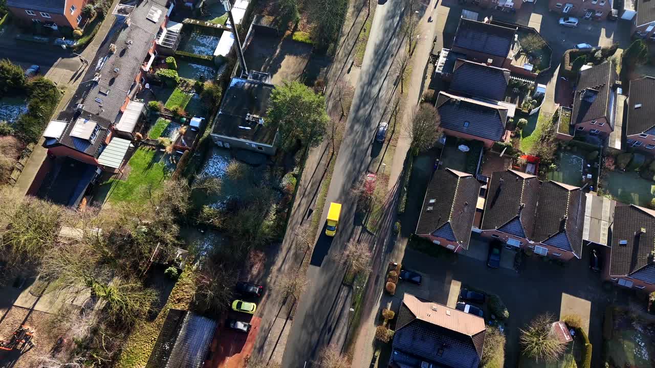 Aerial top down shot of neighborhood with driving bus and DHL Delivery Truck in winter season. Sunny day in german town. Flyover shot.