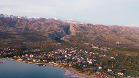 Vista-Aérea-Del-Pueblo-De-Seline-Con-El-Parque-Nacional-De-Velebit-Del-Norte-En-El-Fondo-En-Croacia