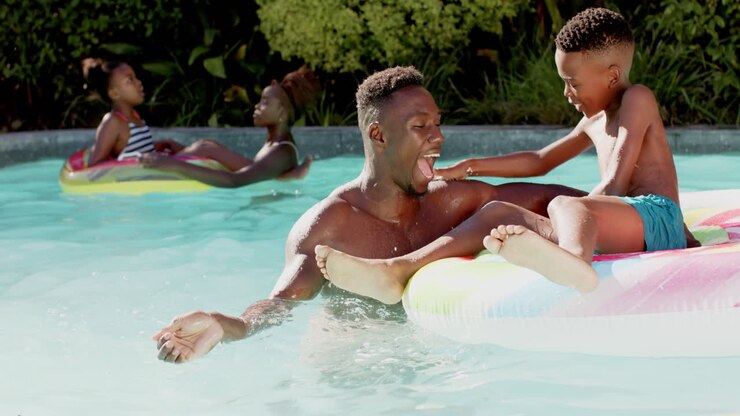 Playing in pool, african american father and son enjoying summer day on inflatable float