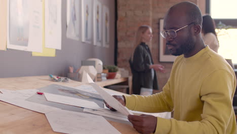 side view of a focused man sitting at drawing desk and working on a new project in an animation studio 1