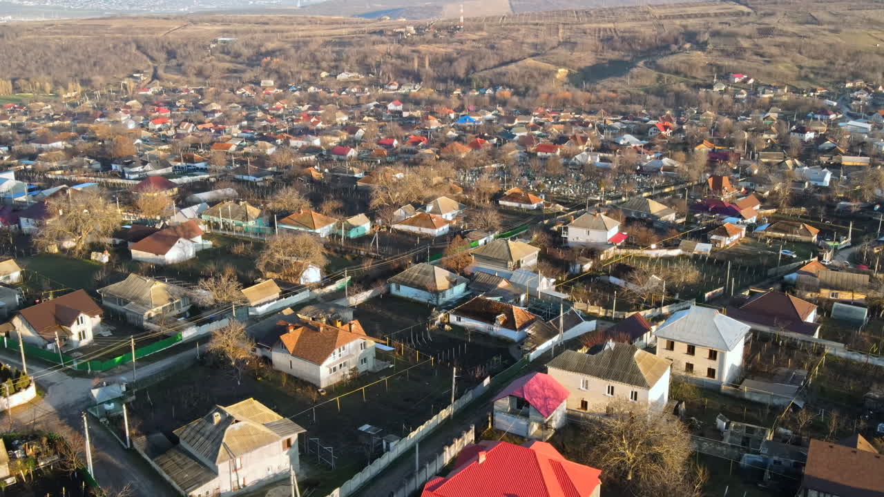 Dronebillede af en landsby. Udsigt over flere boligbygninger, landeveje og nøgne træer. Solrigt vejr. Moldova