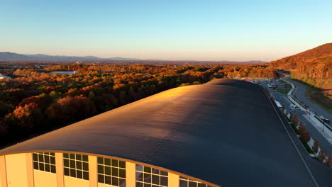 Aerial-establishing-shot-of-large-building-sports-facility-manufacturing-facility-during-golden-hour-light