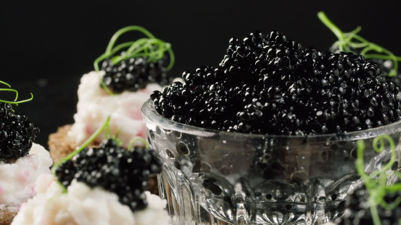 Primo piano di caviale nero e tartine eleganti in rotazione su uno sfondo scuro