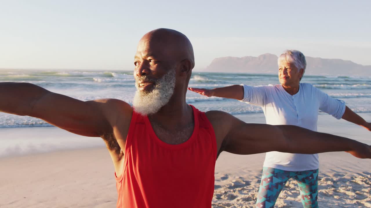 Senior african american couple practising yoga at the beach