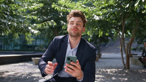 relaxed employee drinking coffee looking smartphone on sunny park close up.