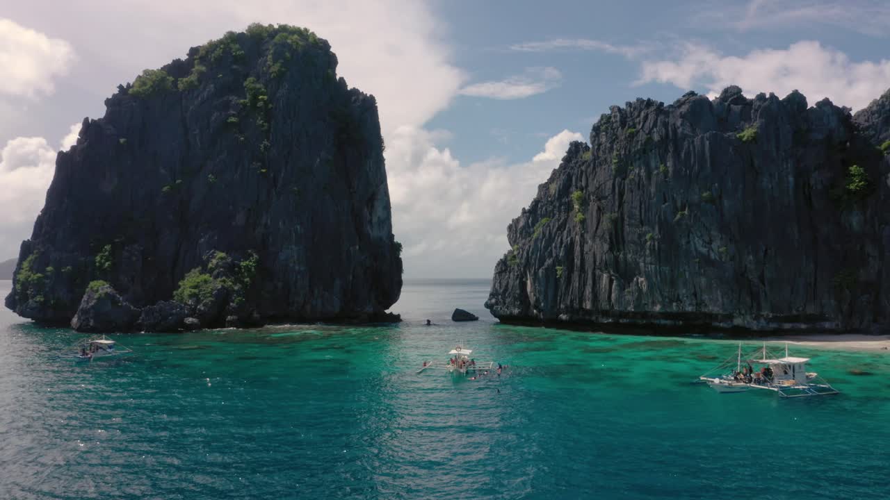 antena de acantilados de piedra caliza, agua turquesa y archipiélago natural con drones volando a través de rocas y pequeñas embarcaciones en el nido, palawan, filipinas