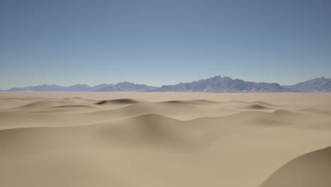 extenso paisaje desértico con dunas de arena onduladas y montañas lejanas