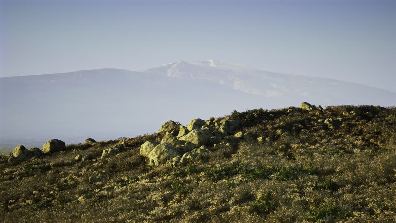 Crinale sereno illuminato da una luce solare delicata e distanti montagne innevate