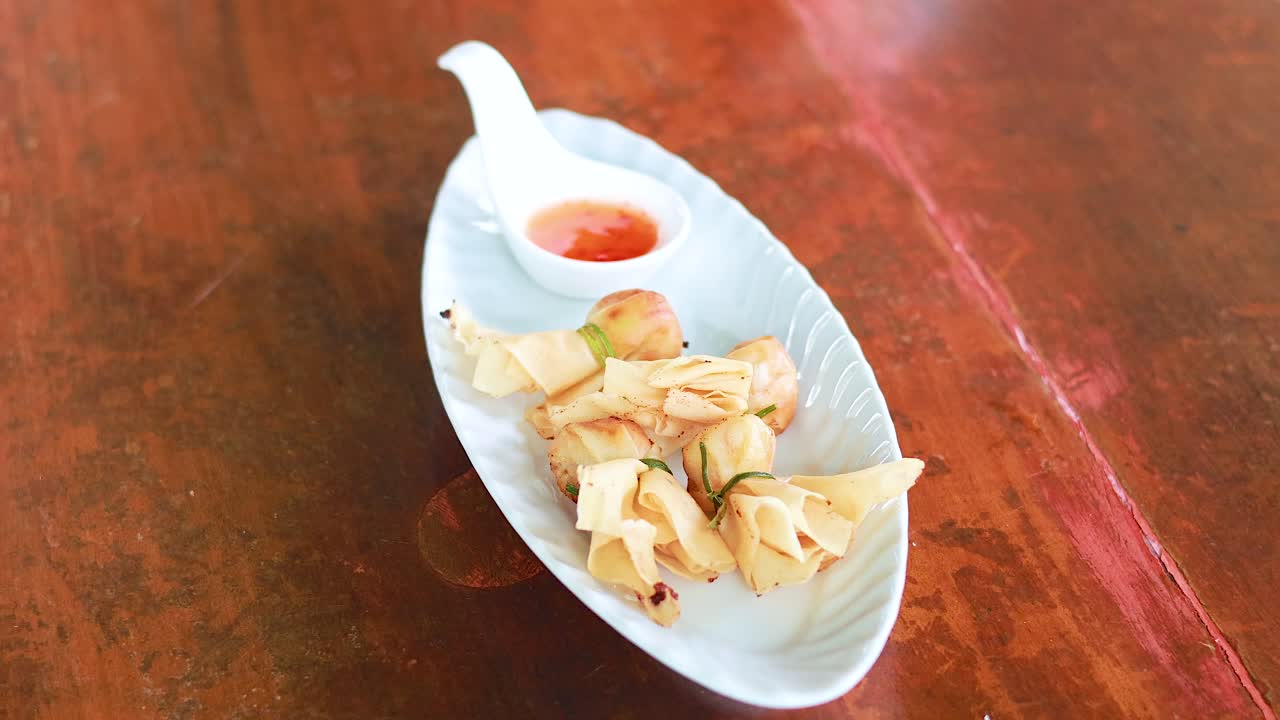 Hand reaching for delicious Thai dumplings