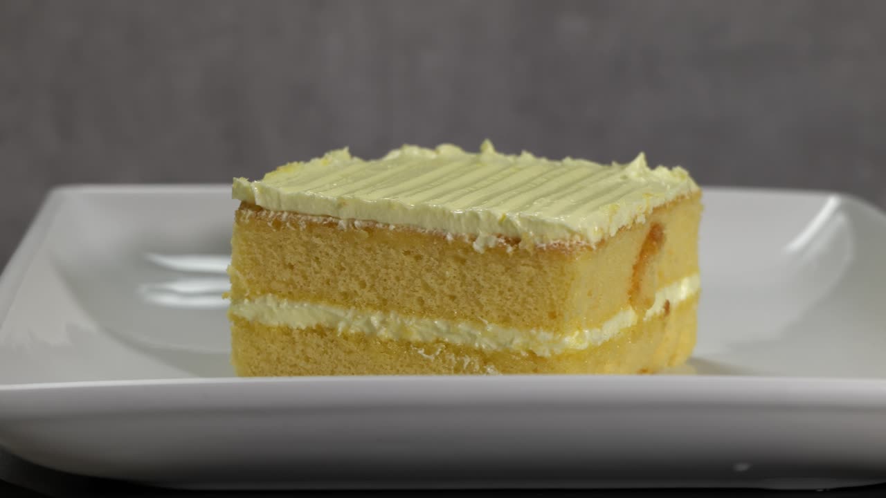 A Slice of Vanilla Cake with Frosting on a White Plate