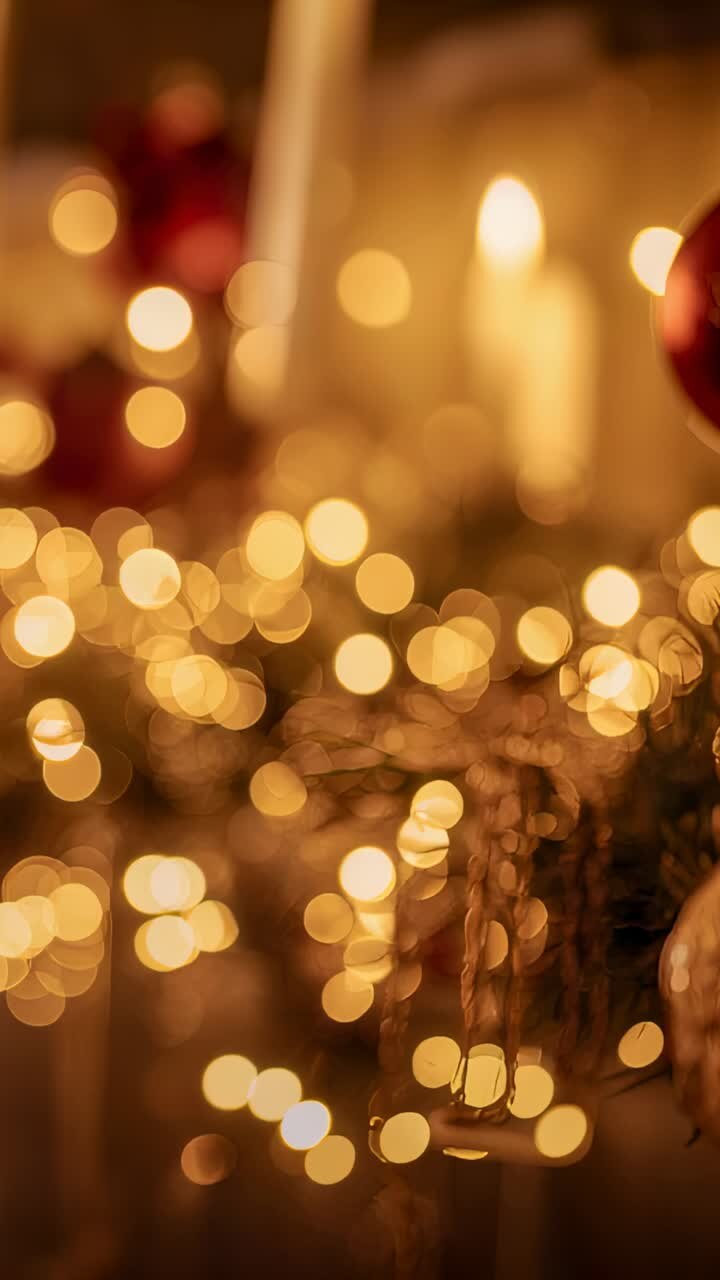 Vertical video: Cam pulling focus revealing red bauble, clear globe, lights and candle on mantel