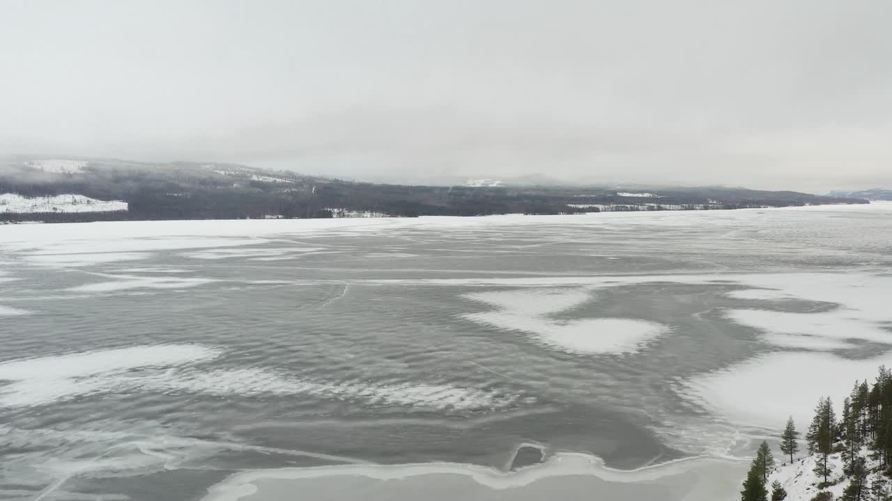 A low to high aerial shot of a partially frozen lake in Sweden