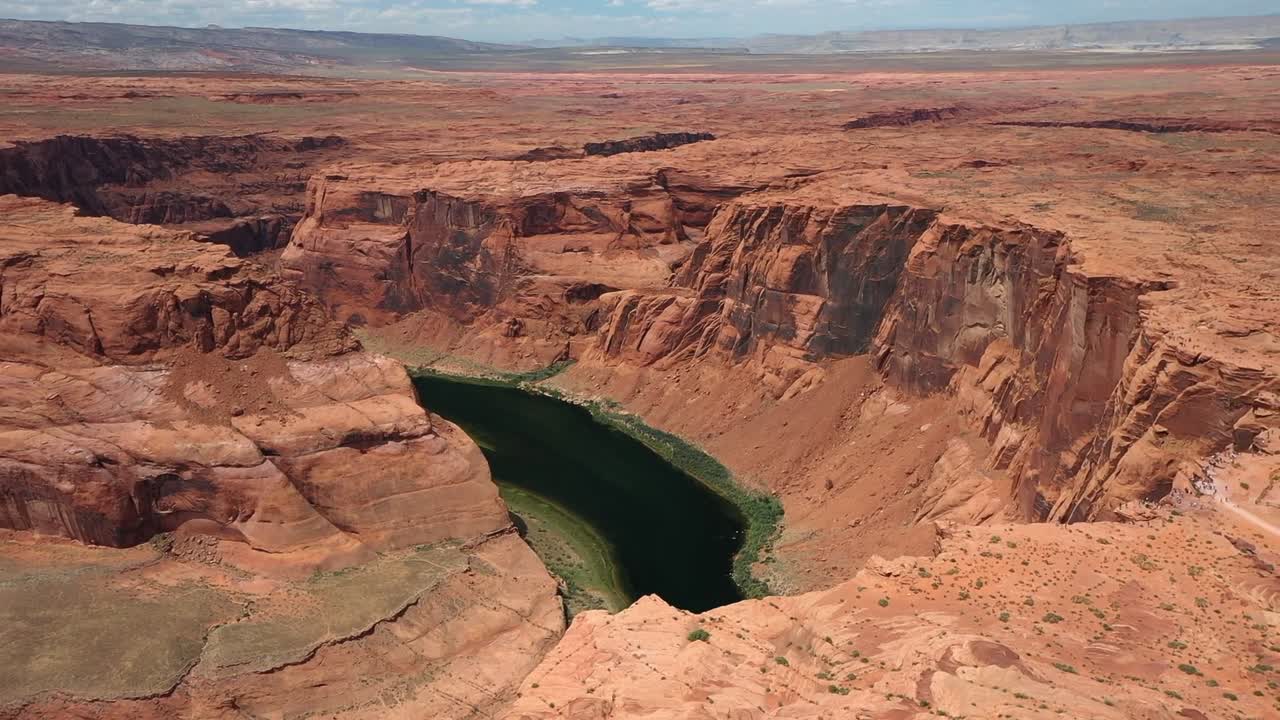 Aerial drone view showing Horseshoe Bend with Colorado River curving around massive red sandstone cliffs near Page Arizona revealing stunning desert canyon landscape and clear sky