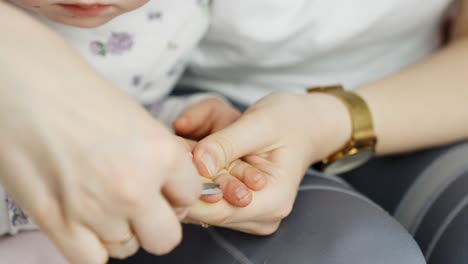baby toddler and parent cutting nails with scissors to trim finger nails close up highlighting hygiene, bonding and parenting care
