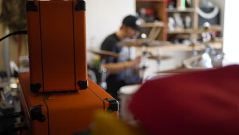 un baterista caucásico en una banda de garaje de rock and roll tocando su instrumento con amplificadores de guitarra y equipo de música a cámara lenta