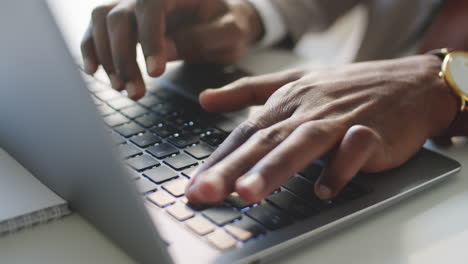 hands of black businessman typing on laptop