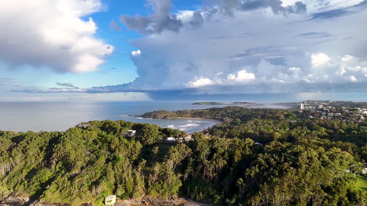 Aerial footage captures lush greenery and coastal views under a bright sky in Charlesworth Bay Beach, Coffs Harbour, Australia