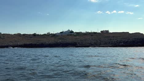 Tour-boat-along-Ionian-coast-of-Salento-in-Apulia-with-Palazzo-Moresco-or-Morro-Palace-in-background,-Italy