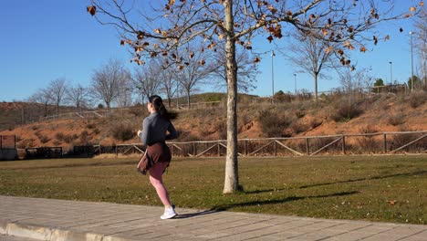 woman running on a park pathway during morning exercise, rear tracking shot