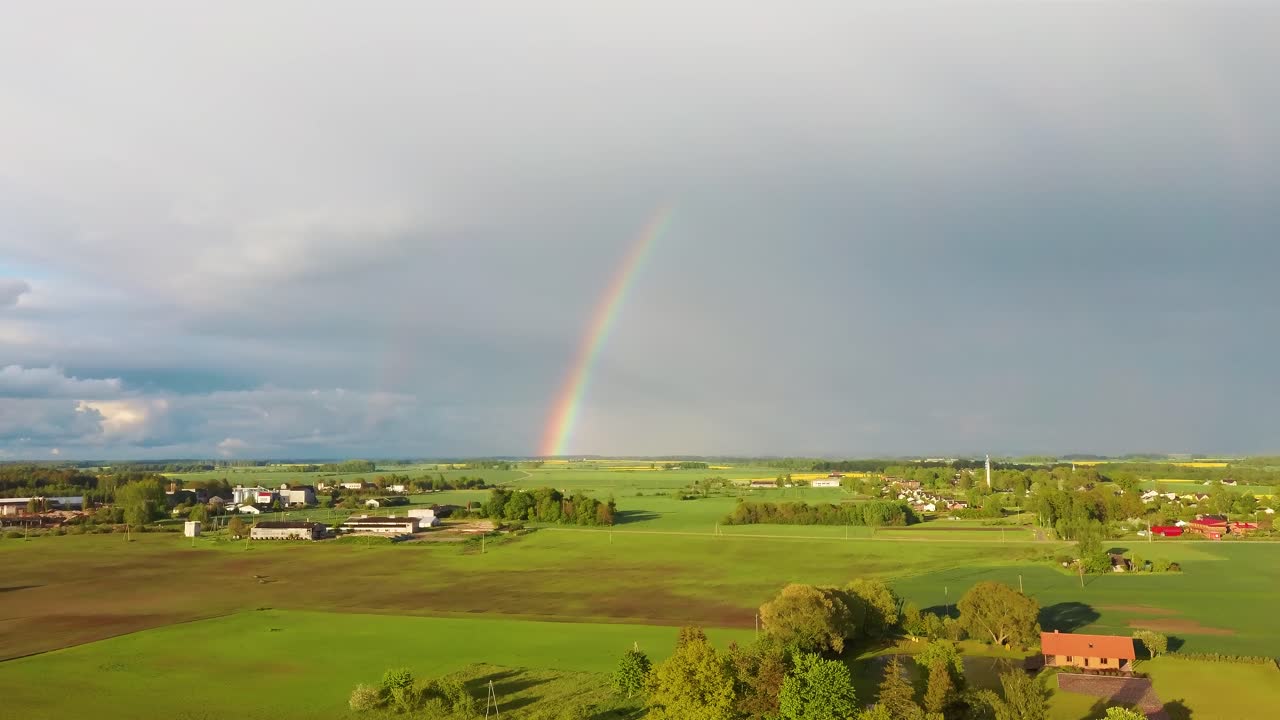 el arco iris sobre el campo de colza con canola floreciente, durante la primavera, vista aérea bajo nubes pesadas antes de la tormenta