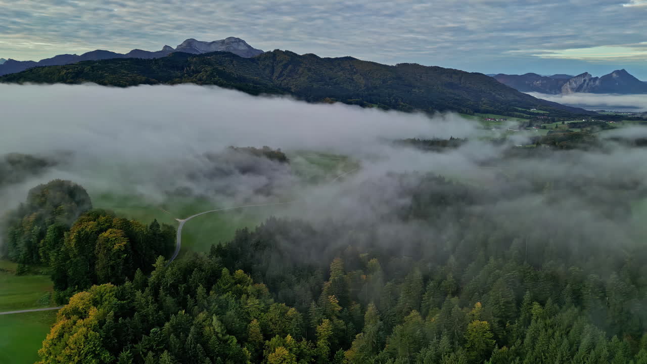 vista aérea de la zona montañosa con bosques envueltos en niebla alrededor del attersee austriaco