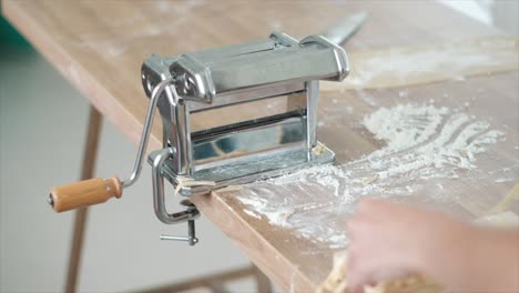 person making fresh homemade pasta with traditional pasta maker machine in slow motion