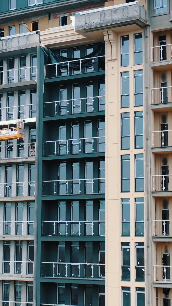 Construction of a modern building in the city. Facade of multistorey apartment house with plastic windows in the city. Building of a new architecture. Vertical video