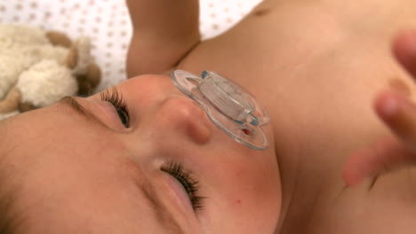 baby lying in crib holding toy