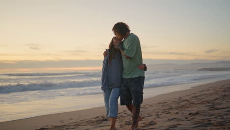 relaxed teenagers walking sunset beach. romantic sweethearts kissing at ocean