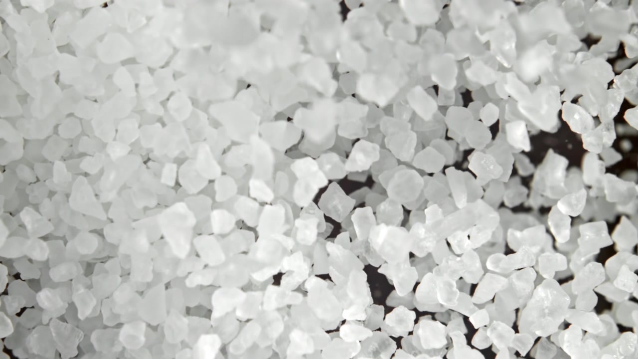 Super slowmotion af hvide salt- eller sukkerkrystaller, der falder