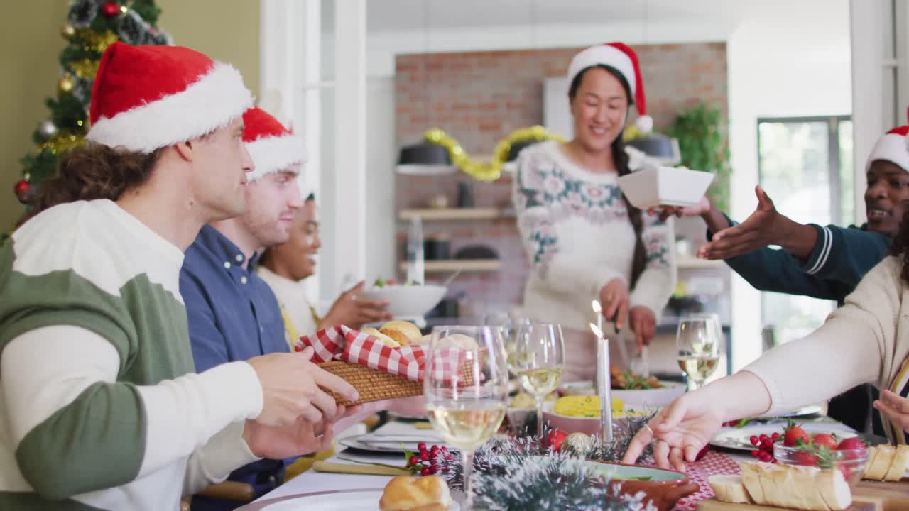 grupo feliz de diversos amigos en sombreros de santa celebrando la comida en tiempo de navidad