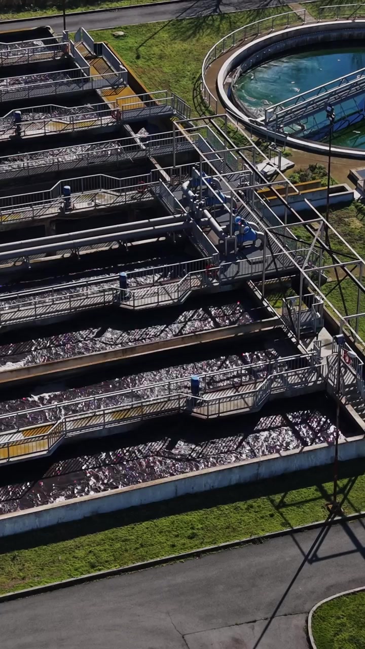 Large wastewater treatment facility with multiple tanks under clear sky