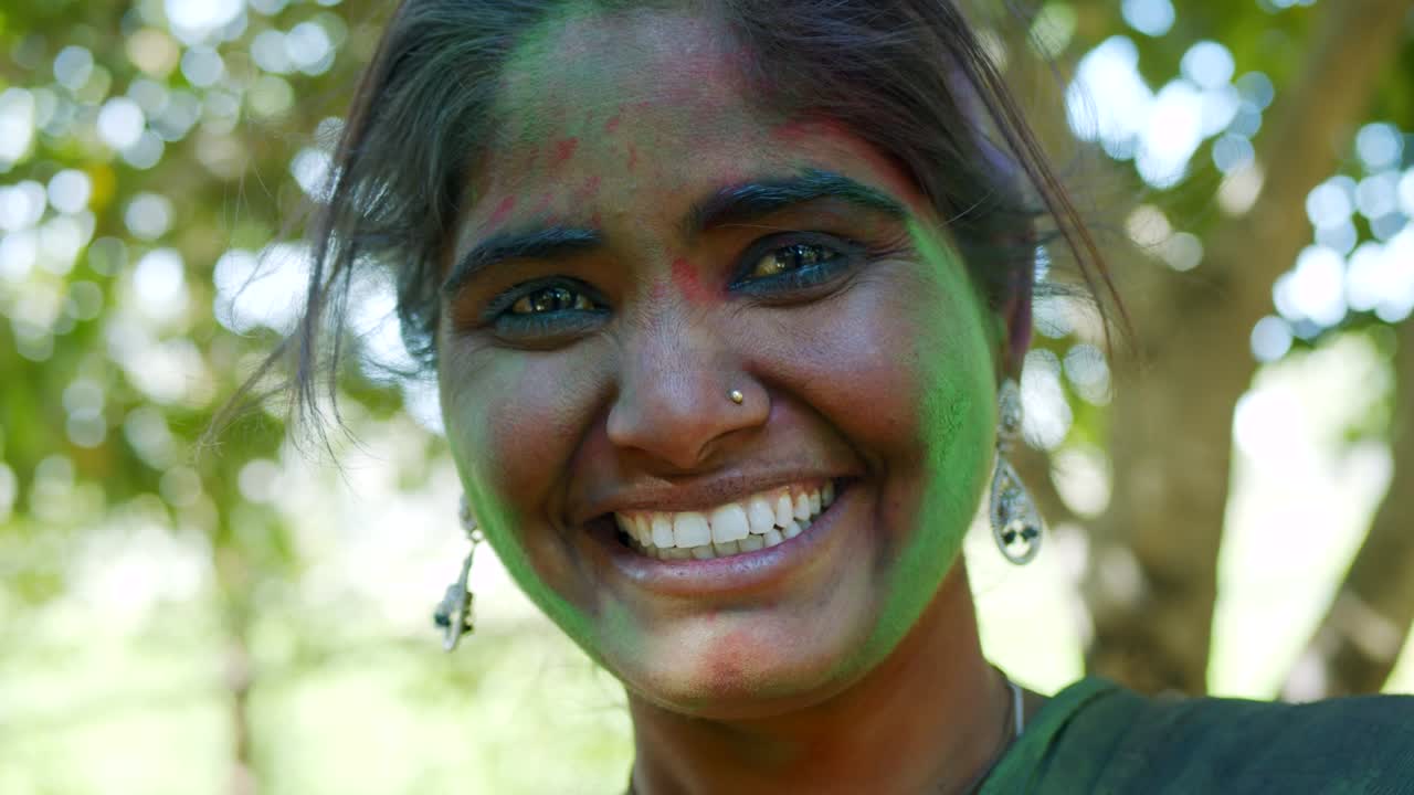 인도 여성의 가까운 얼굴은 밝은 홀리 색으로 얼룩져 있습니다.