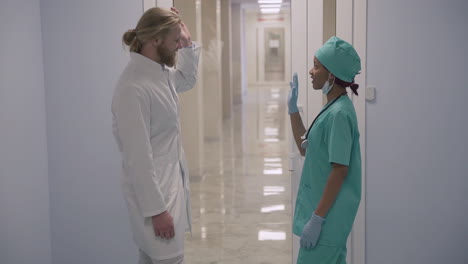 A-Cute-Young-American-Female-Sanitary-Professional-And-A-Young-Doctor-With-Long,-Blond-Hair-High-Five-Their-Hands