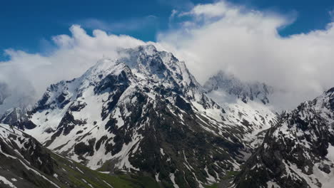 air flight through mountain clouds over beautiful snow-capped peaks of mountains and glaciers.