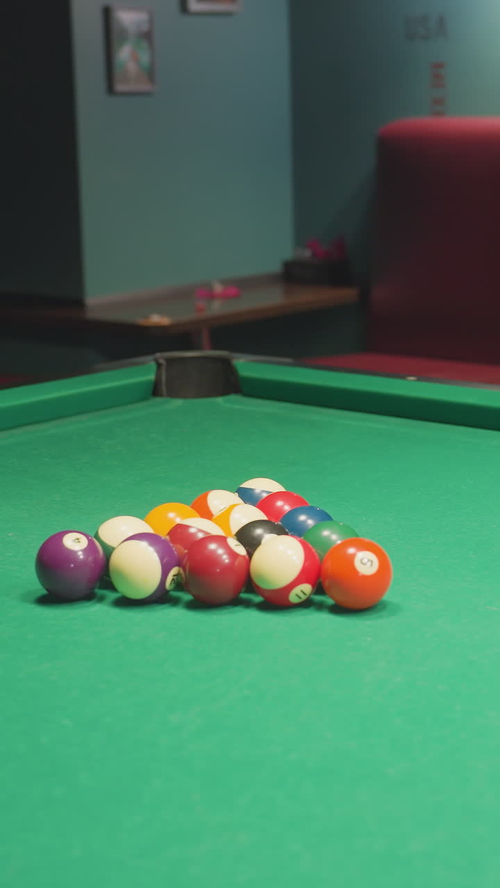 Billiard balls arranged on green pool table, slightly scattered after triangle rack is removed. Close-up shot captures vibrant colors and precise positioning before break shot in casual