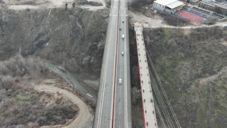 a red bridge spans a narrow gorge, combining modern engineering with natural features. the aerial perspective captures the interplay between human-made structure and rugged terrain