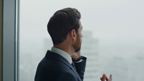 financial consultant talking phone standing at office panoramic window close up