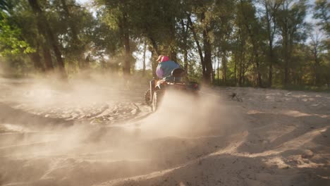 hombre montando un atv en la arena recogiendo un pilar de polvo. tipo moderno conduciendo una quadbike