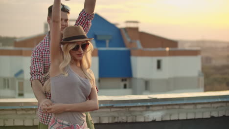 pareja de amor en camisas a cuadros rojas se mueven en baile en el techo. chica con cerveza girando en baile con su novio ruso. ella mueve su cuerpo hermosamente