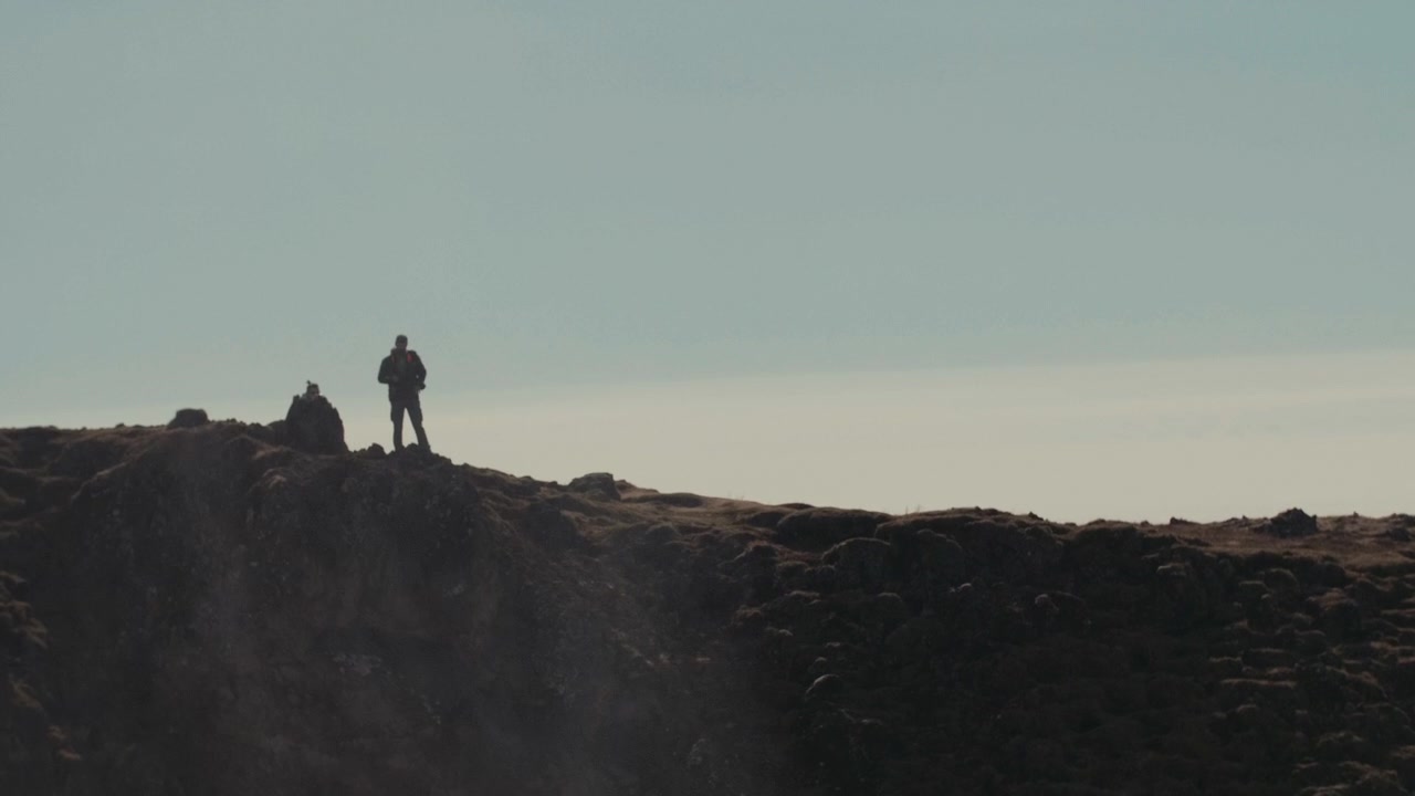 Silhouette of a Hiker Standing on a Rocky Mountain Ridge