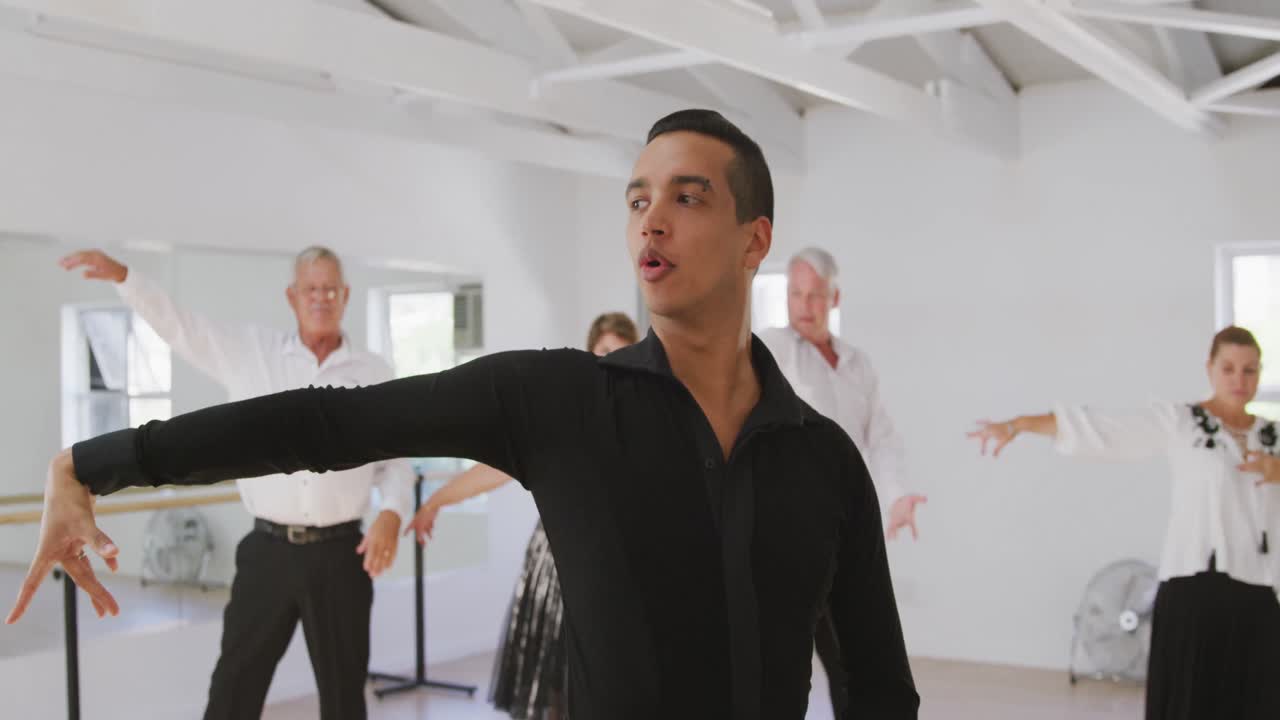 mixed race male dance teacher taking a ballroom dancing class at a dance studio